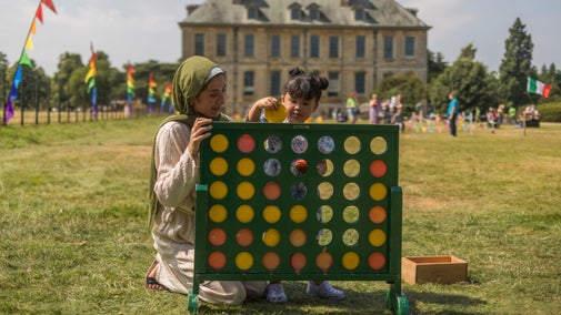 A parent and her child sitting down to play a giant Four in a Row game during the Summer of Play event at Belton Estate, Lincolnshire